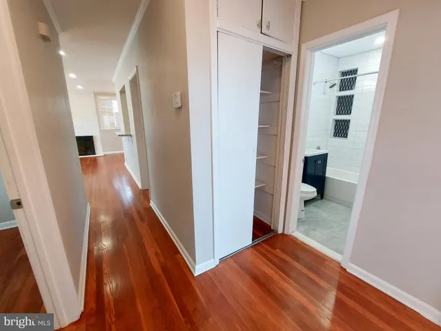 a view of a hallway with wooden floor and a bathroom