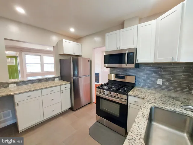 a kitchen with granite countertop a stove sink and refrigerator