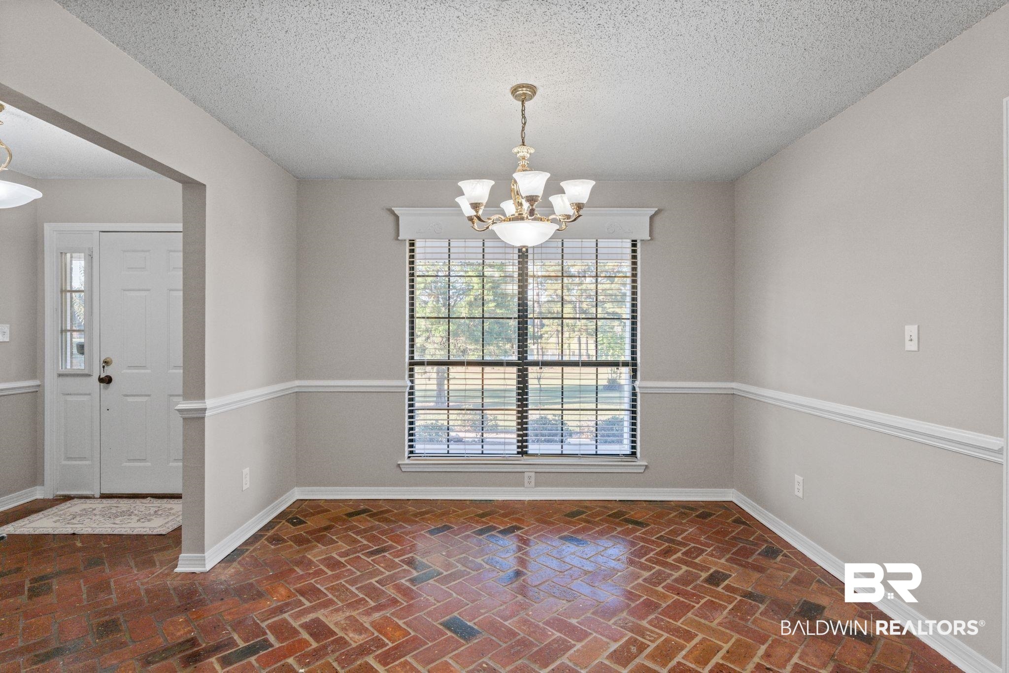 888 Mobile Cut-Off Road St. Stephens, AL 36569 - Photo 16 of 54 Empty room with a textured ceiling, brick floors, and a chandelier
