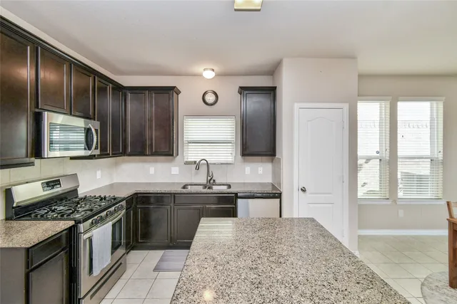 a kitchen with stainless steel appliances granite countertop a sink stove and refrigerator