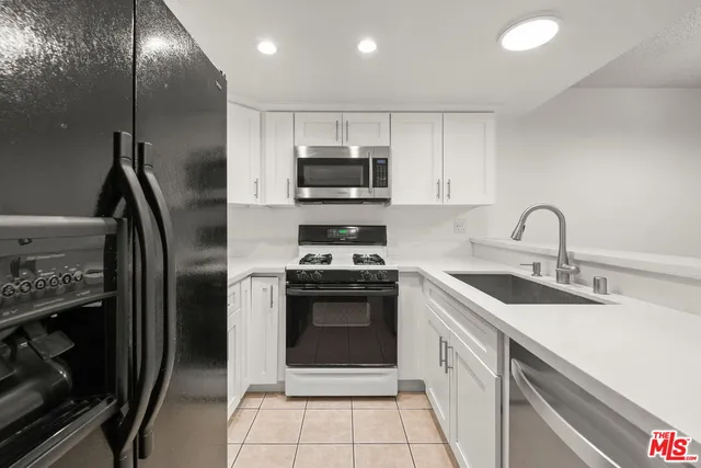 a kitchen with granite countertop a stove a sink and a microwave
