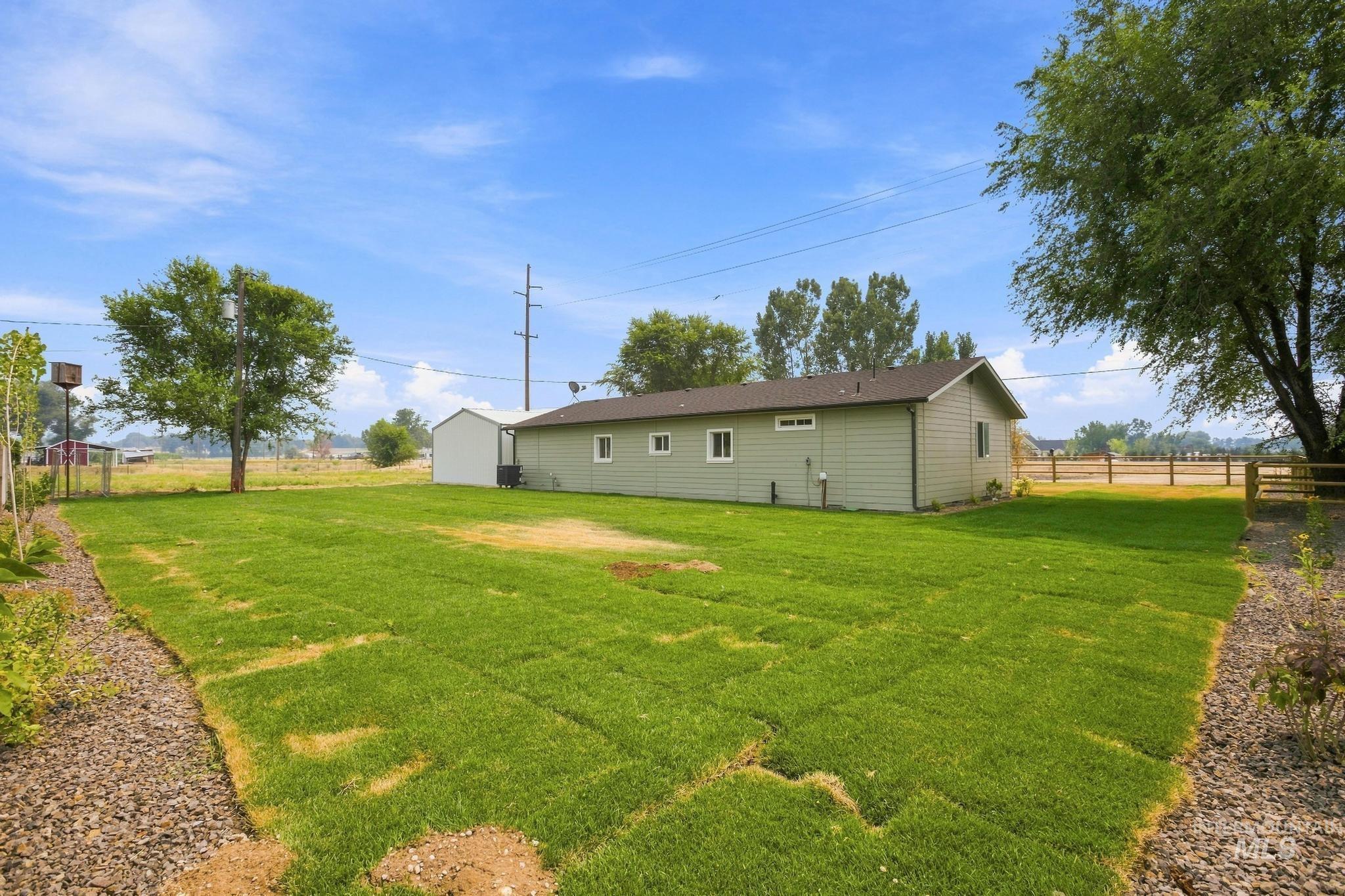 14666 Willis Road Caldwell, ID 83607 - Photo 42 of 50 Expansive backyard featuring freshly laid sod, mature trees, and a gravel border