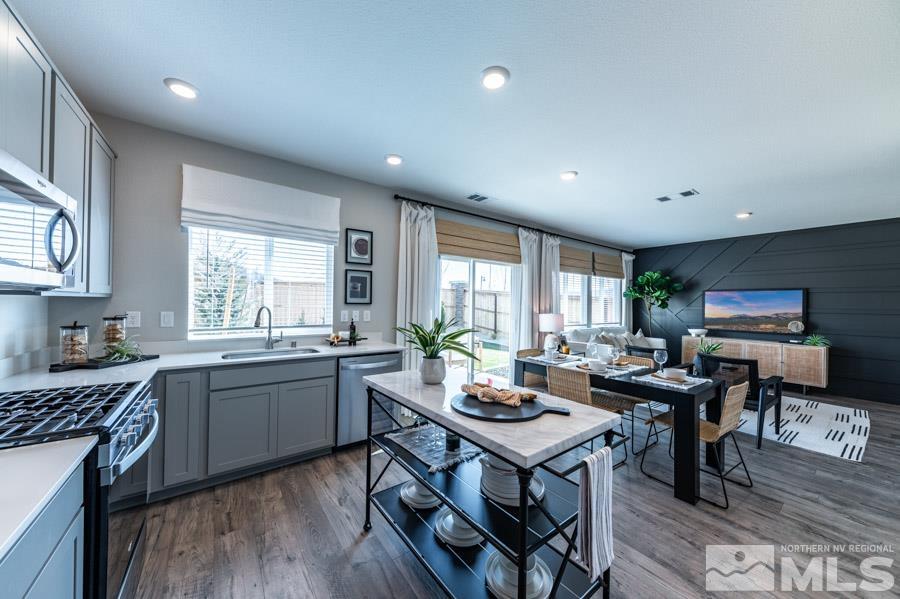7814 Wandering Way, Unit LOT #167 Reno, NV 89506 - Photo 3 of 18 a kitchen with a stove a sink a kitchen island with a dining table and chairs