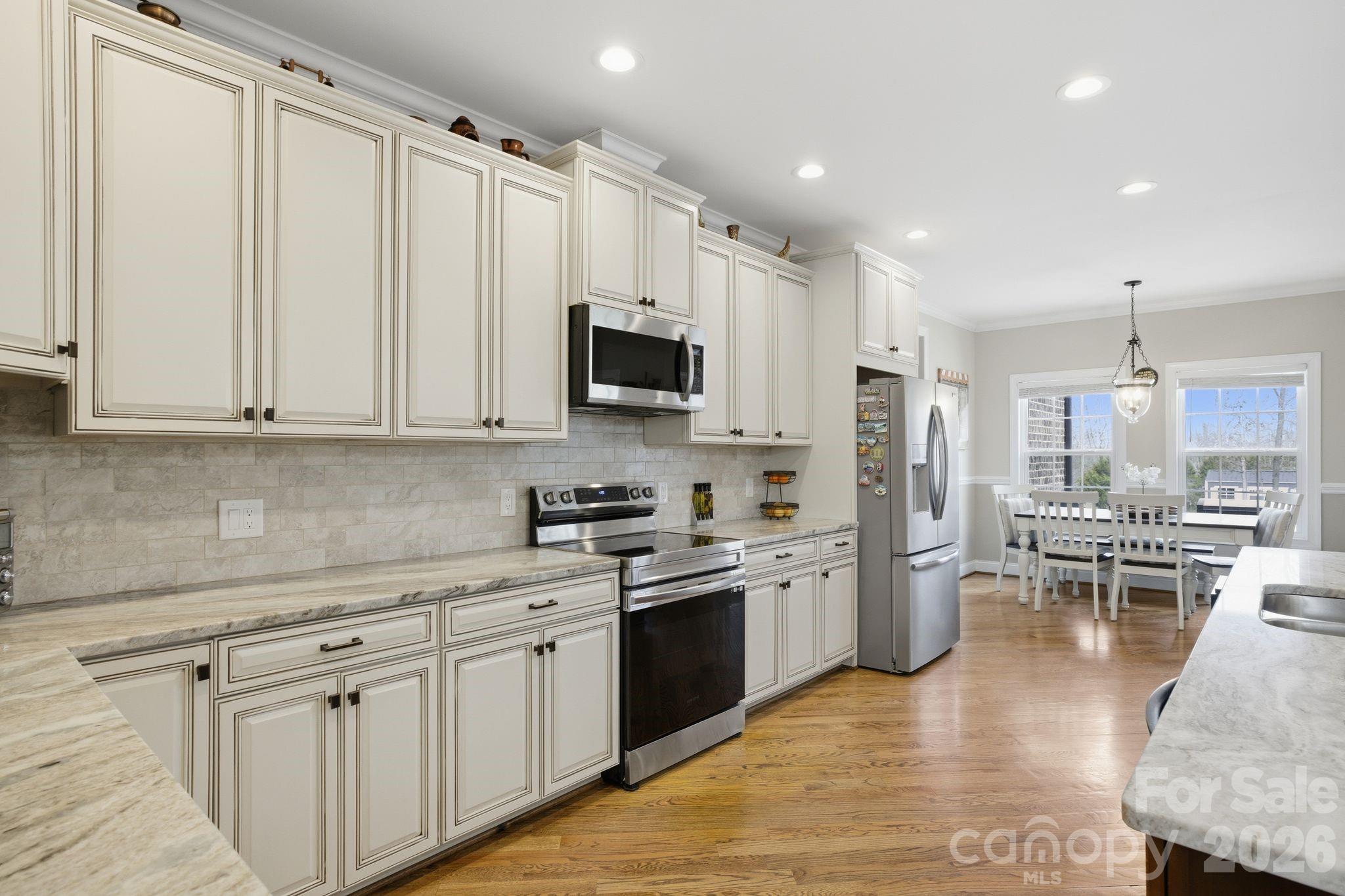1370 Null Road, Unit 4 Lincolnton, NC 28092 - Photo 4 of 47 a kitchen with stainless steel appliances granite countertop a refrigerator a stove top oven a sink a dining table and chairs with white cabinets