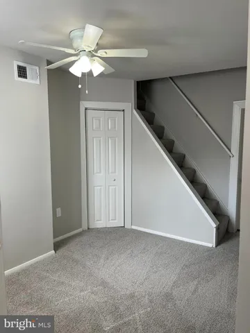 a view of an empty room with chandelier fan