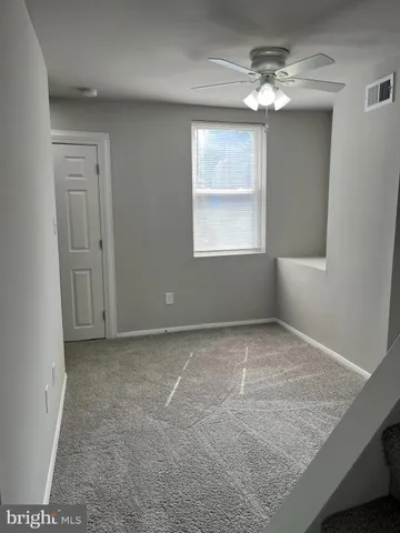 en empty room with windows and chandelier fan