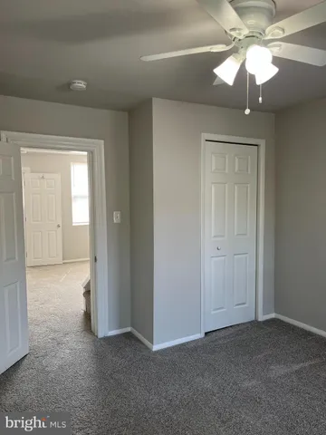 an empty room with a chandelier fan and windows