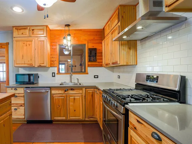 a kitchen with stainless steel appliances granite countertop a stove a sink and a microwave