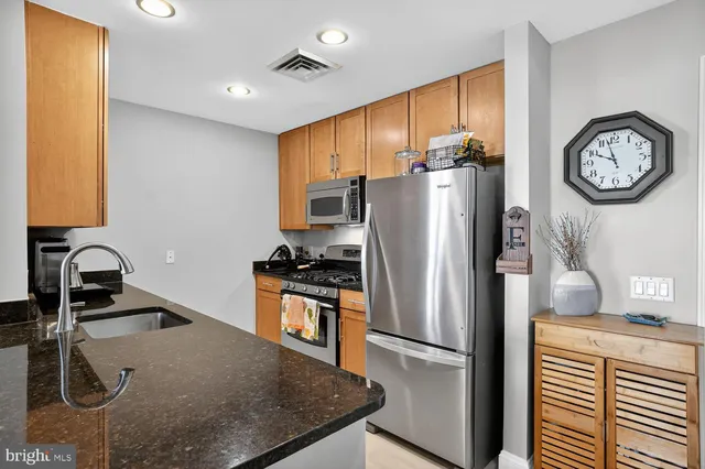 a kitchen with stainless steel appliances granite countertop a refrigerator a stove and a sink with wooden floor