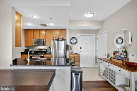 a kitchen with stainless steel appliances granite countertop a refrigerator a stove a sink and a dining table with wooden floor