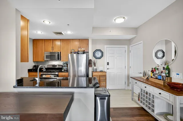 a kitchen with stainless steel appliances granite countertop a refrigerator a stove a sink and a dining table with wooden floor