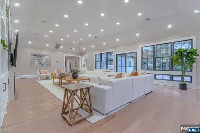 a living room with furniture and potted plants with wooden floor