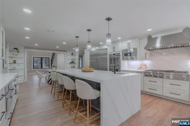 a kitchen with stainless steel appliances kitchen island granite countertop a table chairs sink and cabinets