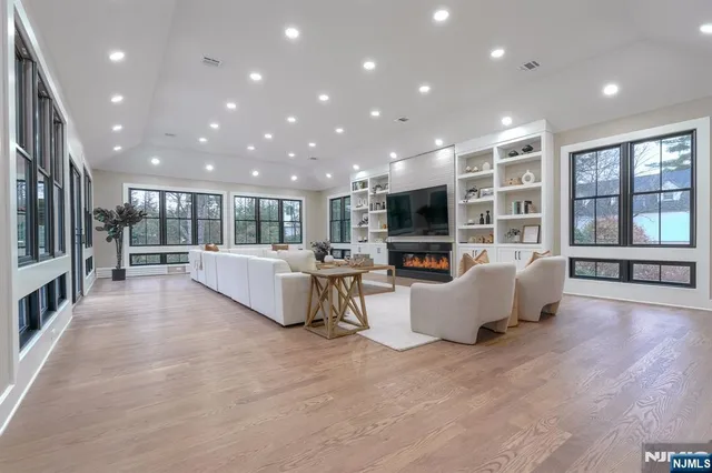 a large living room with stainless steel appliances furniture a large window and a view of kitchen