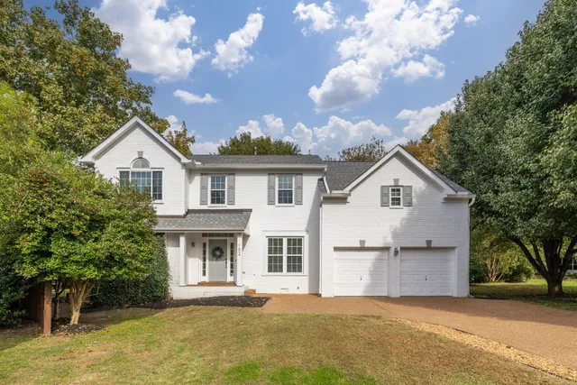 a front view of a house with a garden and trees