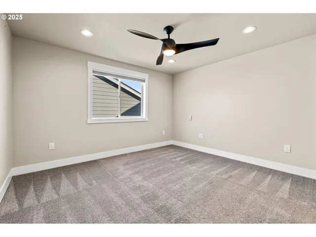 a view of an empty room and chandelier fan