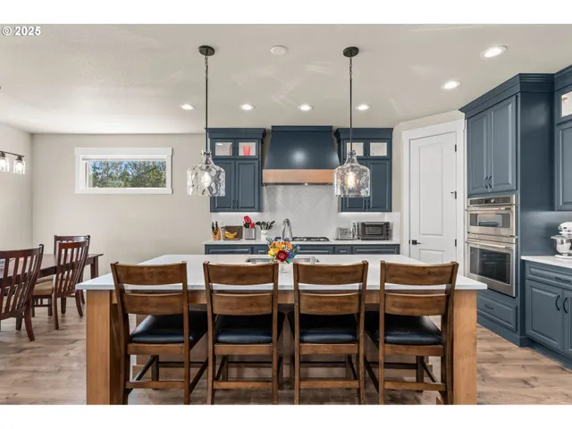 a kitchen with kitchen island a stove a sink dishwasher and a refrigerator with wooden floor