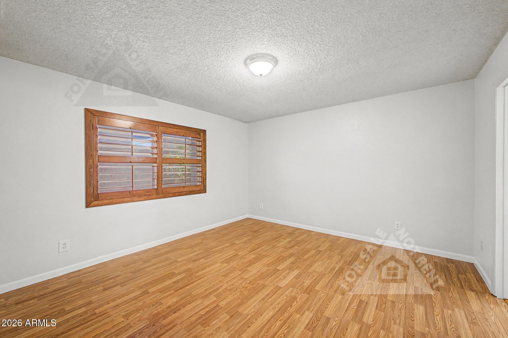 912 East Villa Rita Drive Phoenix, AZ 85022 - Photo 17 of 27 a view of an empty room with wooden floor and a window