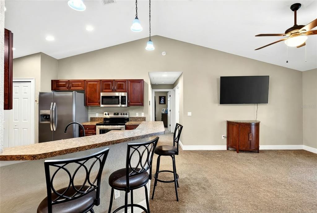 3001 Southwest 173rd Street Road Ocala, FL 34473 - Photo 14 of 28 a kitchen with stainless steel appliances kitchen island granite countertop a dining table chairs microwave and sink