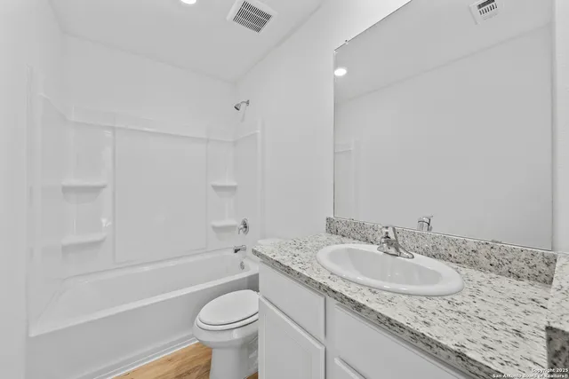 a bathroom with a granite countertop sink a toilet and bathtub