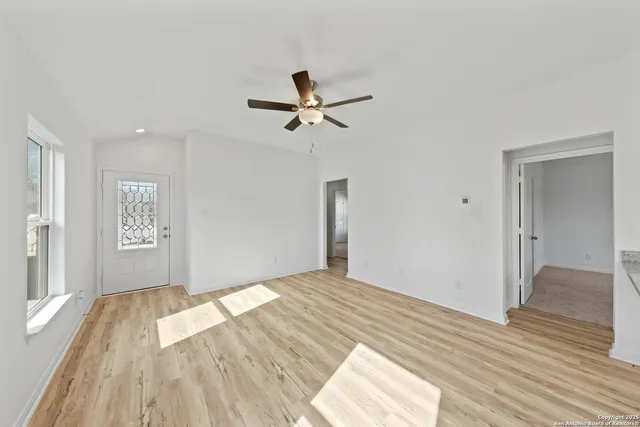 a view of empty room with wooden floor and fan