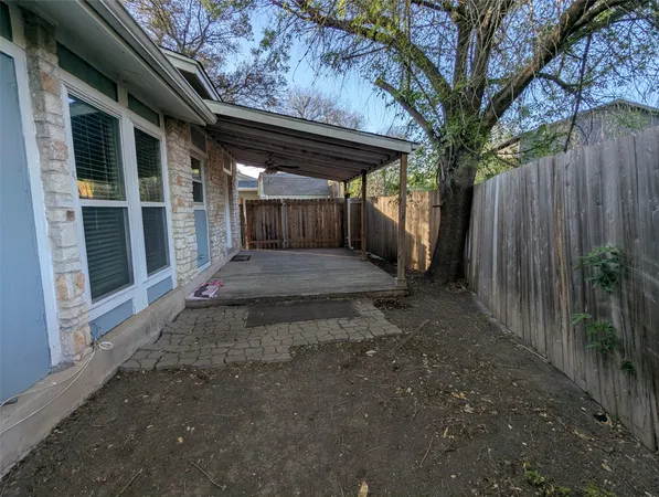a view of backyard with plants and wooden fence