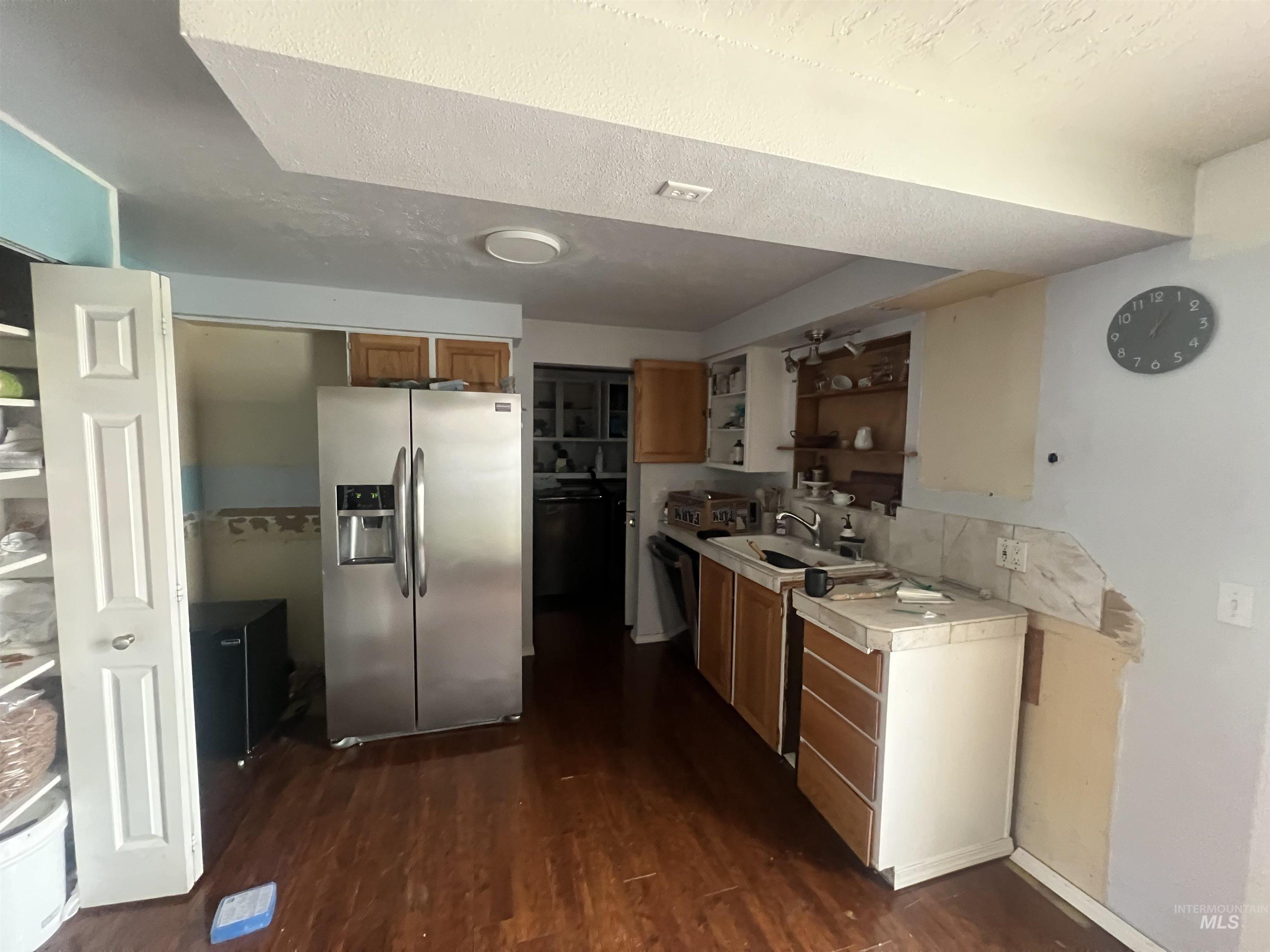 908 13th Street Kamiah, ID 83536 - Photo 4 of 12 Kitchen featuring stainless steel fridge with ice dispenser, light countertops, a textured ceiling, dark wood-style flooring, and open shelves