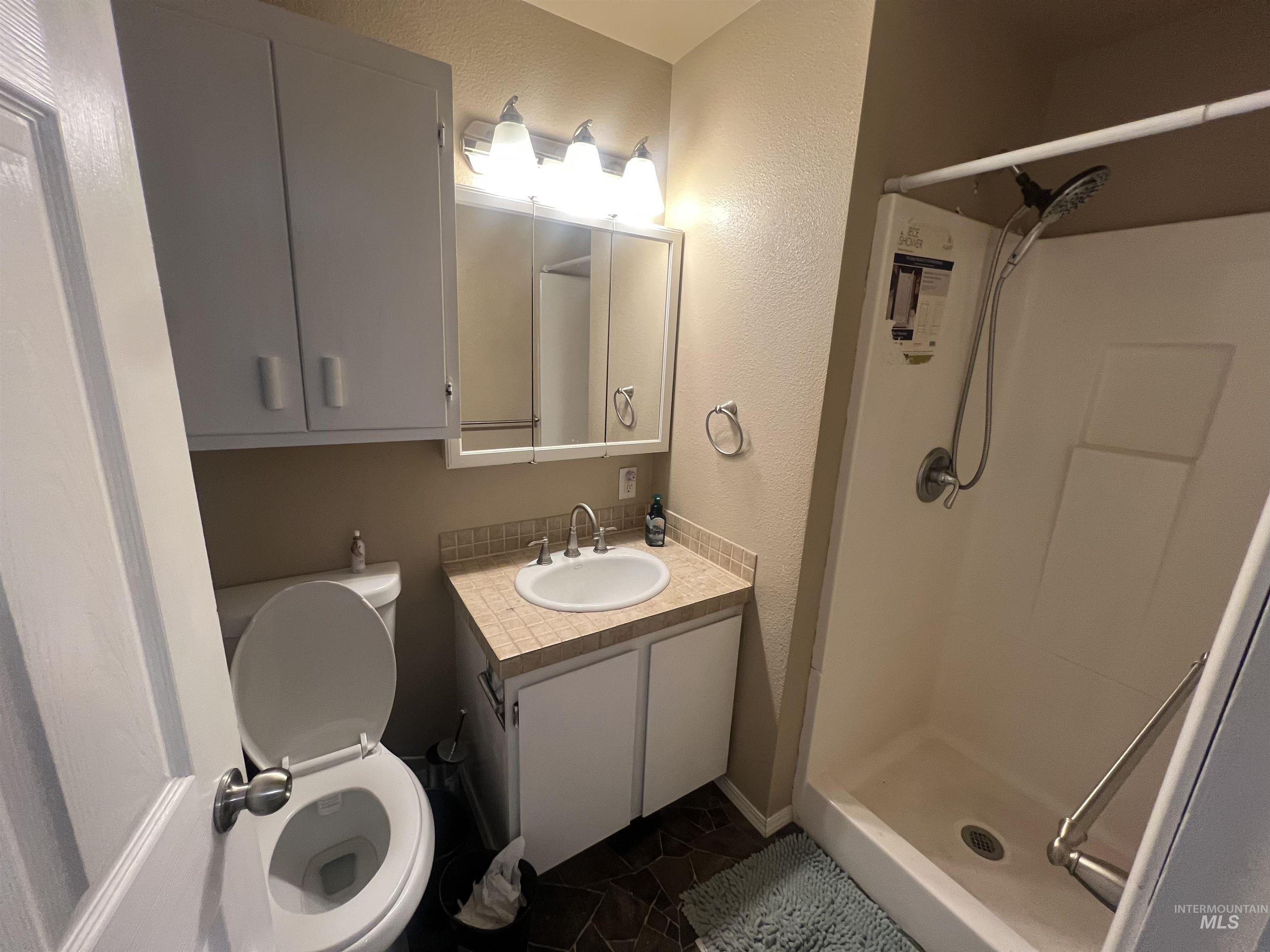 908 13th Street Kamiah, ID 83536 - Photo 10 of 12 Bathroom with a textured wall, a stall shower, and vanity