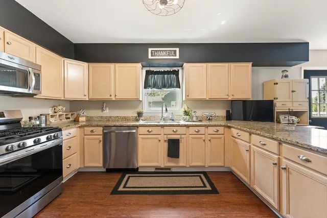 a kitchen with granite countertop cabinets stainless steel appliances a sink and a window