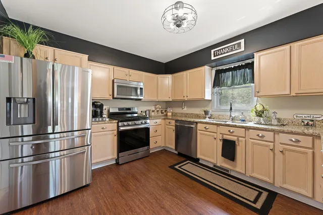a kitchen with granite countertop stainless steel appliances a stove top oven and a refrigerator