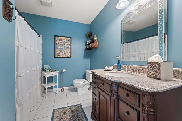 a bathroom with a granite countertop sink a toilet and a mirror