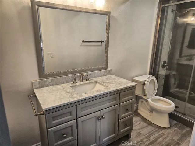a bathroom with a granite countertop sink toilet and mirror