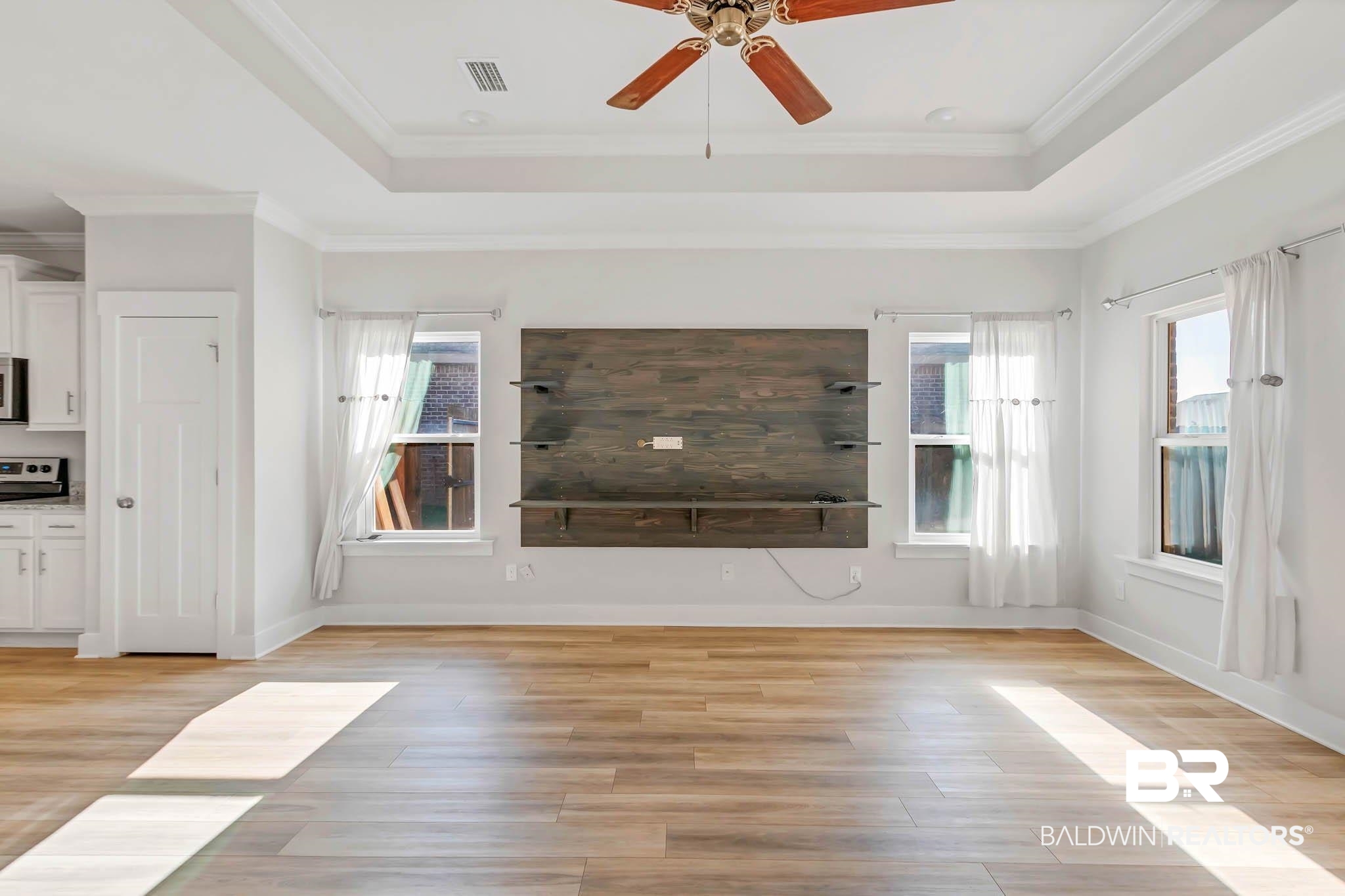 16461 Prado Loop Loxley, AL 36551 - Photo 18 of 78 Unfurnished living room featuring a tray ceiling, light wood-style floors, ornamental molding, and a ceiling fan