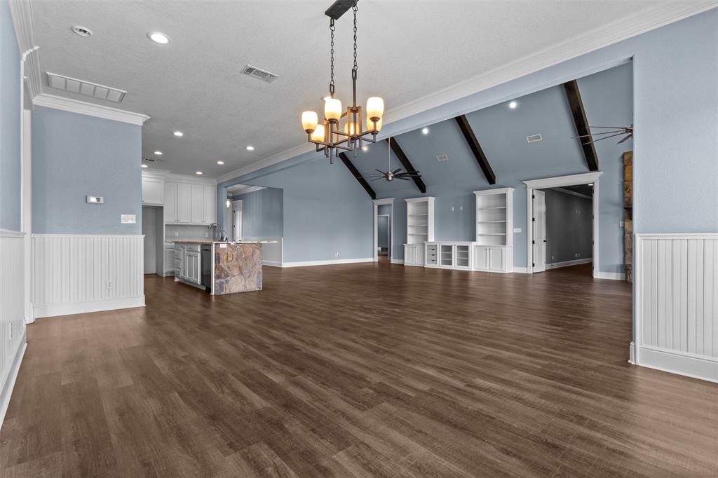 910 County Road 1111 Decatur, TX 76234 - Photo 10 of 40 Unfurnished living room with ornamental molding, dark wood-type flooring, ceiling fan, a chandelier, and wainscoting