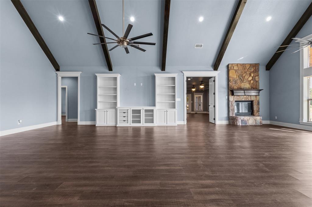 910 County Road 1111 Decatur, TX 76234 - Photo 11 of 40 Unfurnished living room featuring a ceiling fan, a fireplace, dark wood-type flooring, high vaulted ceiling, and beam ceiling