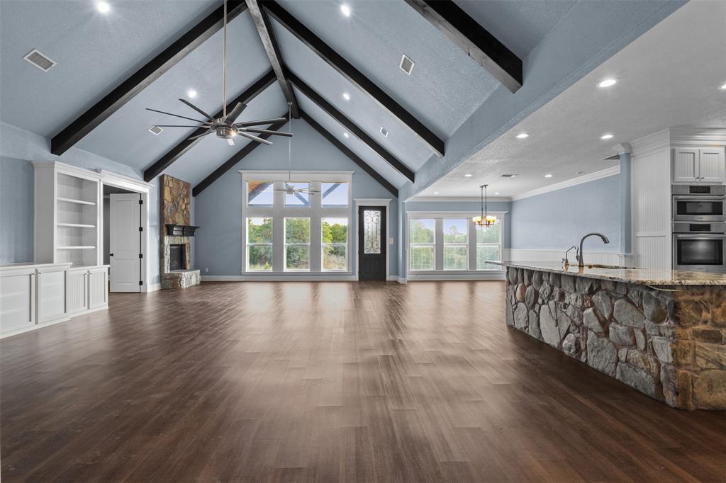 910 County Road 1111 Decatur, TX 76234 - Photo 14 of 40 Unfurnished living room with beamed ceiling, a ceiling fan, high vaulted ceiling, a fireplace, and dark wood-style flooring
