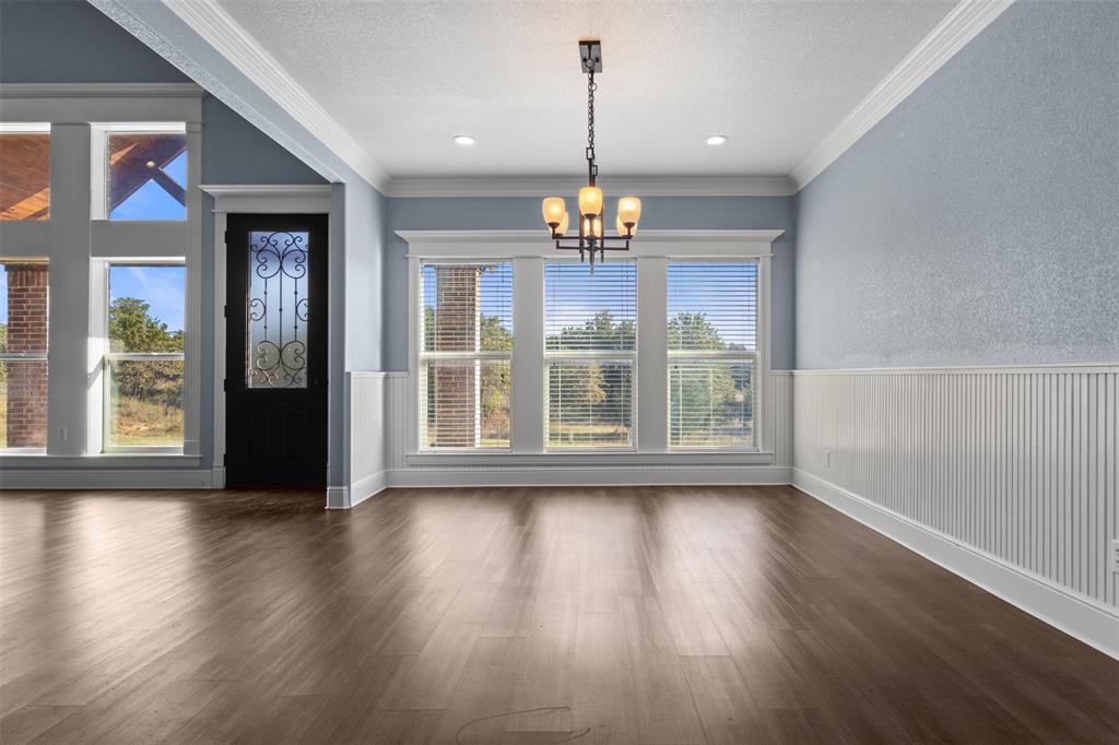 910 County Road 1111 Decatur, TX 76234 - Photo 15 of 40 Unfurnished dining area featuring dark wood-style flooring, ornamental molding, a chandelier, and a textured ceiling