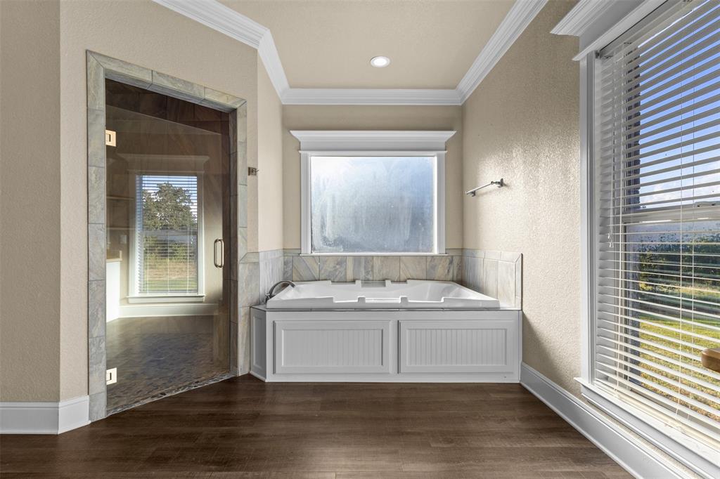 910 County Road 1111 Decatur, TX 76234 - Photo 29 of 40 Bathroom with a textured wall, a bath, dark wood-type flooring, crown molding, and a shower stall