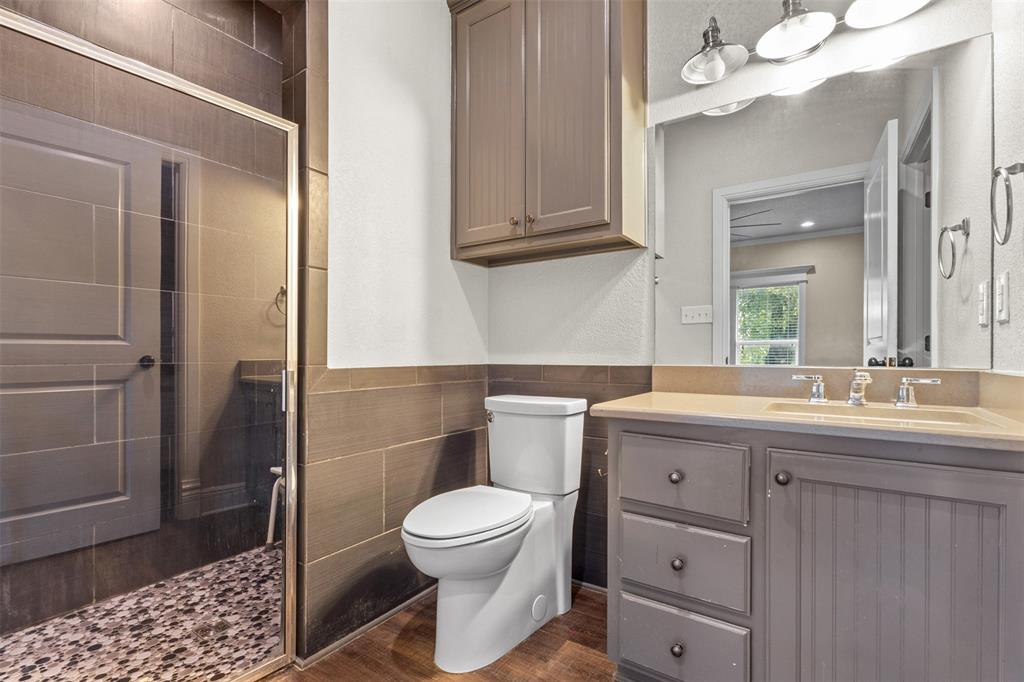 910 County Road 1111 Decatur, TX 76234 - Photo 35 of 40 Full bathroom with a shower stall, vanity, tile walls, wainscoting, and dark wood-style flooring