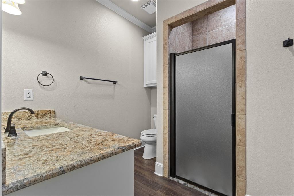 910 County Road 1111 Decatur, TX 76234 - Photo 36 of 40 Bathroom featuring vanity, dark wood-style floors, crown molding, a textured wall, and a stall shower