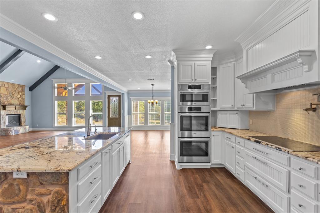 910 County Road 1111 Decatur, TX 76234 - Photo 39 of 40 Kitchen featuring open floor plan, dark wood-style flooring, light stone countertops, white cabinets, and a textured ceiling