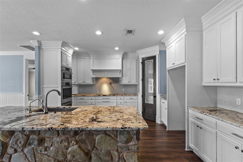 910 County Road 1111 Decatur, TX 76234 - Photo 7 of 40 Kitchen featuring light stone countertops, recessed lighting, ornamental molding, dark wood-style flooring, and white cabinets