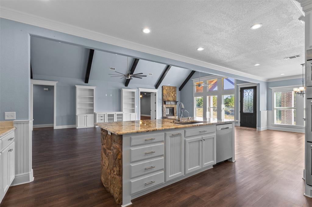 910 County Road 1111 Decatur, TX 76234 - Photo 40 of 40 Kitchen featuring open floor plan, light stone countertops, a kitchen island with sink, a wainscoted wall, and recessed lighting