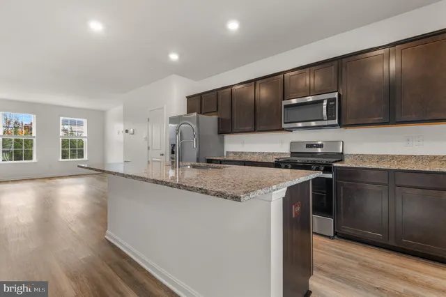 a kitchen with stainless steel appliances granite countertop a stove a sink and a microwave