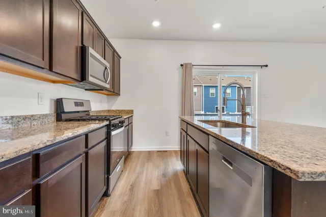 a large kitchen with stainless steel appliances granite countertop a lot of counter space and wooden floor