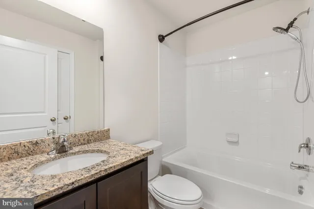 a bathroom with a granite countertop sink a toilet and shower