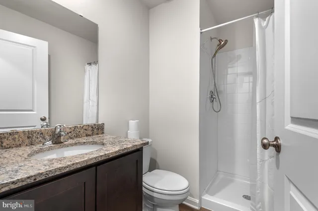 a bathroom with a granite countertop sink toilet and shower