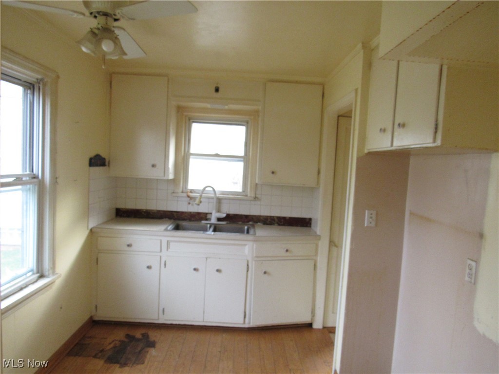 4550 Effie Road Cleveland, OH 44105 - Photo 6 of 29 Kitchen featuring backsplash, light wood finished floors, ceiling fan, and white cabinets