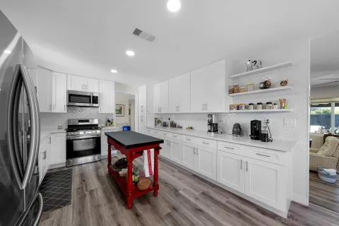 a kitchen with stainless steel appliances a stove top oven a sink dishwasher and a refrigerator with wooden floor