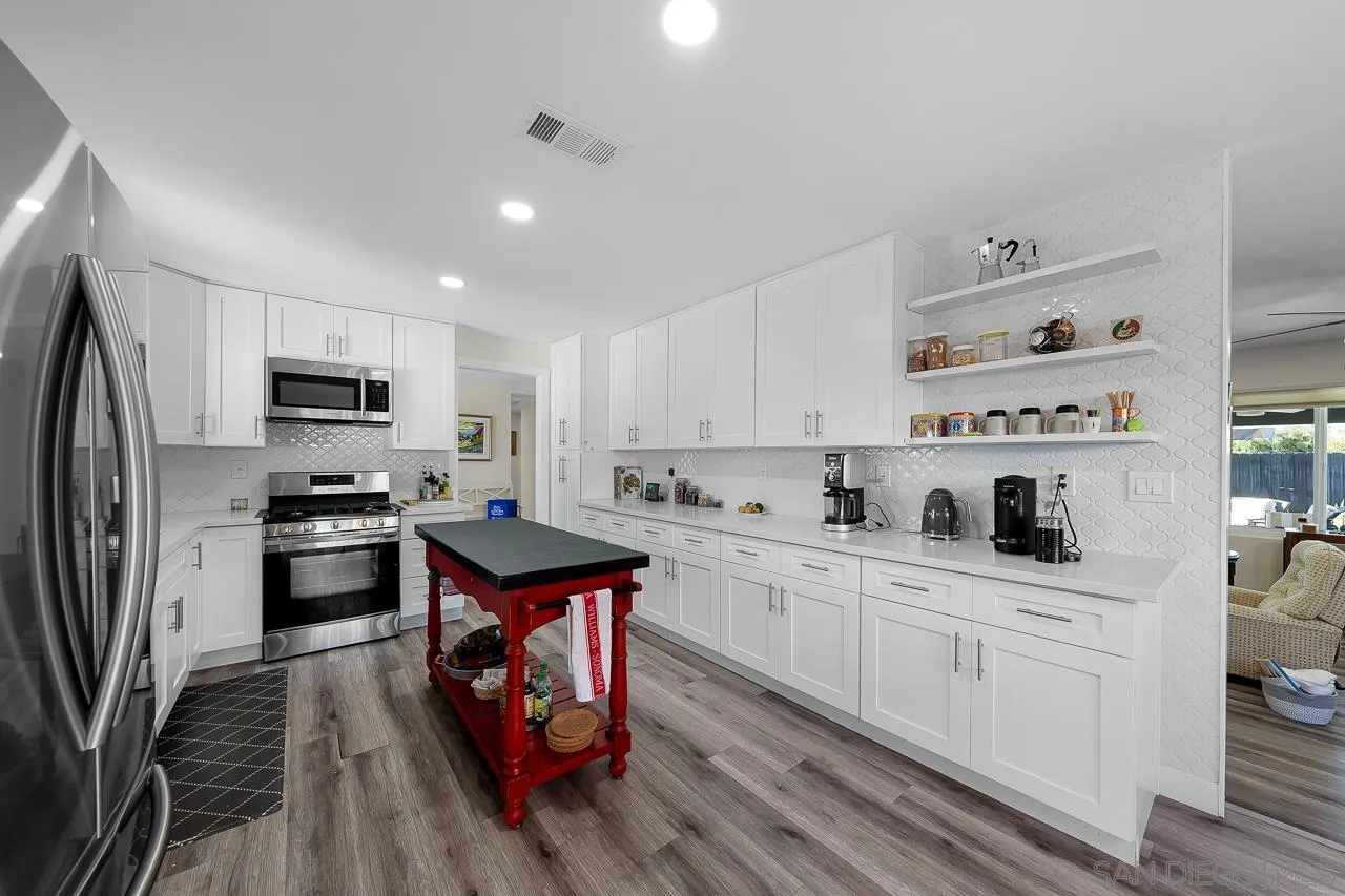 1761 Harvard Street Chula Vista, CA 91913 - Photo 11 of 41 a kitchen with stainless steel appliances a stove top oven a sink dishwasher and a refrigerator with wooden floor